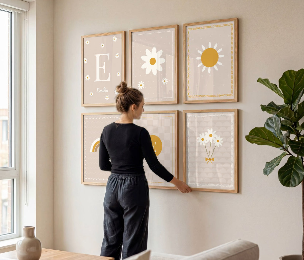Frau hängt ein Namensposter-Set mit Gänseblümchen und Sonne an die Wand